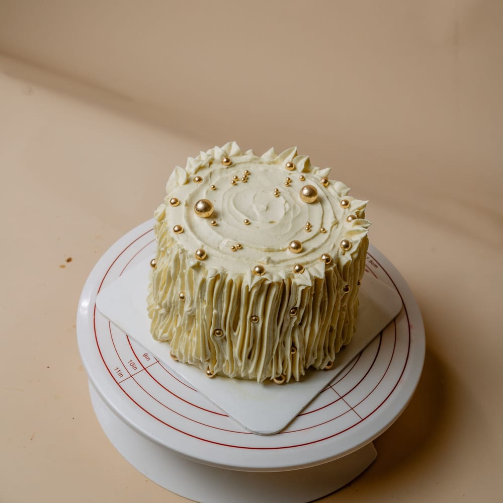 An ivory buttercream Madge Treats cake with gold pearls
