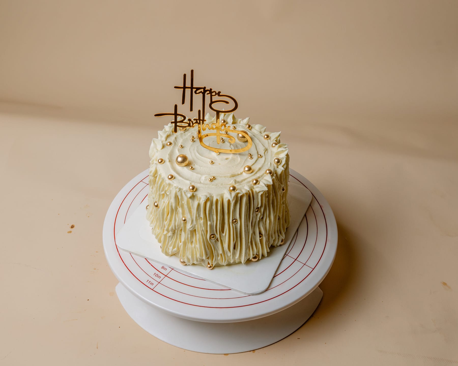 Celebration cake finished with a gold Happy Birthday topper